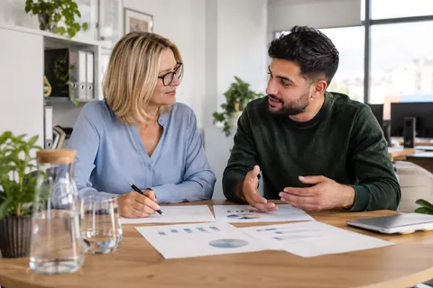 Zwei Personalverantwortliche besprechen die Teamplanung an einem Tisch im Büro.