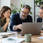 Drei Personalverantwortliche prüfen gemeinsam Informationen auf einem Laptop.